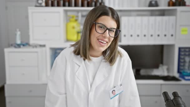 Uma Cientista Sorrindo Laboratório Com Microscópio Óculos Labcoat Morena Profissional — Vídeo de Stock