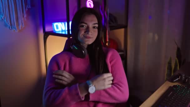 Uśmiechnięta Młoda Kobieta Skrzyżowanymi Ramionami Nosząca Słuchawki Neonowym Pokoju Gier — Wideo stockowe