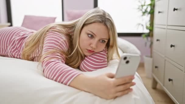 Задумчивая Молодая Женщина Лежит Кровати Просматривая Свой Смартфон Уютной Спальне — стоковое видео