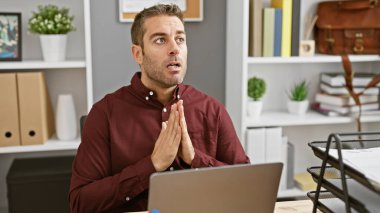 Ofiste sakallı İspanyol bir adam umut dolu ve dua ediyor.