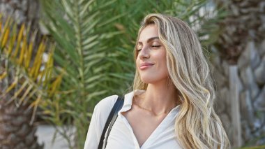 Güzel beyaz kadın meditasyon yapıyor, gözleri kapalı, temiz havayı derin bir şekilde soluyor, mükemmel dengeli, rahat, yaz güneşinin altında yemyeşil parkta güneşleniyor, pozitif, sakin bir aura yayıyor..