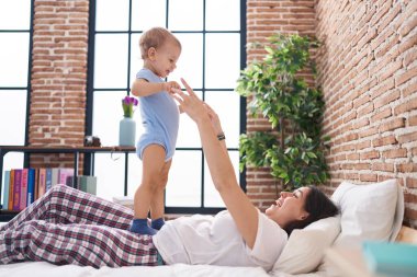 Anne ve oğlu yatakta uzanıp yatak odasında oynuyorlar.