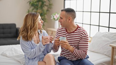 Kadın ve erkek yatak odasında kahve içerler.