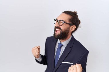 Sakallı, takım elbiseli ve kravatlı İspanyol bir adam çok mutlu ve heyecanlı, kolları havada, gülümseyen ve başarı için bağıran, kazanan bir jest yapıyor. kutlama konsepti. 