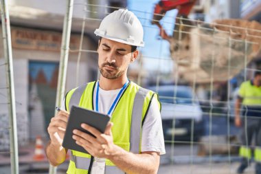 Young hispanic man architect drawing on touchpad at street