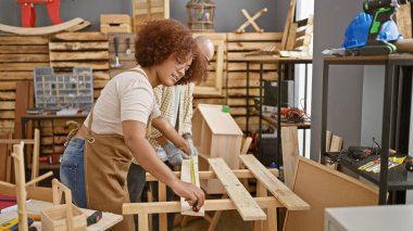 İki profesyonel marangoz, ahşap işçiliğinde suç ortağı, hızlı koşan bir marangozun atölyesindeki sağlam bir keresteyi ölçüyor.