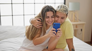 Yatak odasında akıllı telefon kullanan güzel bir çift.