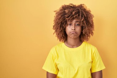 Sarı arka planda duran kıvırcık saçlı, genç İspanyol kadın depresyonda ve üzüntüden ağlıyor, kızgın ve korkmuş. hüzünlü ifade. 