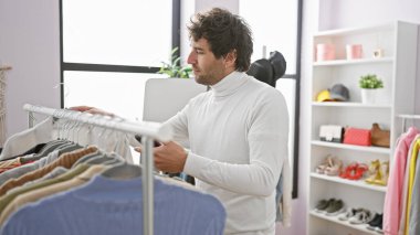 Modern bir gardıropta giysileri karıştıran yakışıklı genç adam moda ve yaşam tarzını resmediyor..