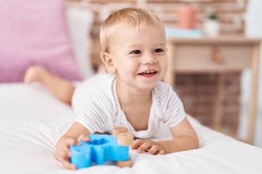 Sevimli çocuk yatakta kendinden emin bir şekilde gülümsüyor.