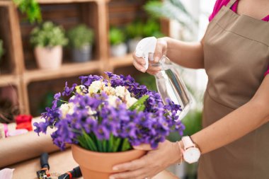 Middle age chinese woman florist using diffuser working at flower shop