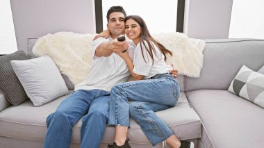 Mutlu bir çift içeride eğleniyor, uzaktan kumandayla koltukta rahatça oturuyorlar..