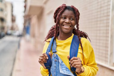 African american woman student smiling confident wearing backpack at street