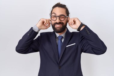 Sakallı, takım elbiseli, kravatlı, kulaklarını parmaklarıyla kapatan, gürültülü müzik sesi için rahatsız edici ifadeleri olan İspanyol bir adam. sağır kavramı. 