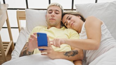 Yatak odasında akıllı telefon kullanan güzel bir çift.