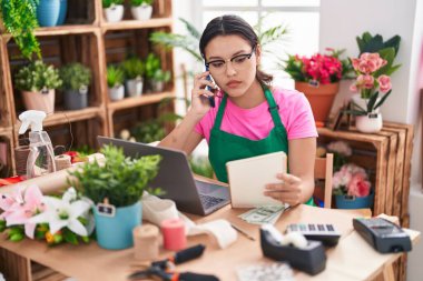 Genç İspanyol çiçekçi kadın çiçekçi çiçekçide telefon okuyup not defteri okuyor.