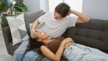 Asyalı bir kadının beyaz bir adamla kanepede uzanıp onu sıcacık bir oturma odasında okşarken mahrem bir anı.