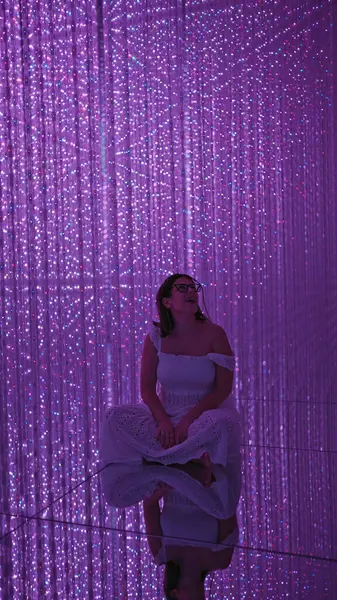 Gülümseyen güzel İspanyol kadın modern müzede fütürist sergiler sergiliyor. Lazerler, ışıklar, en iyi yenilikler.!