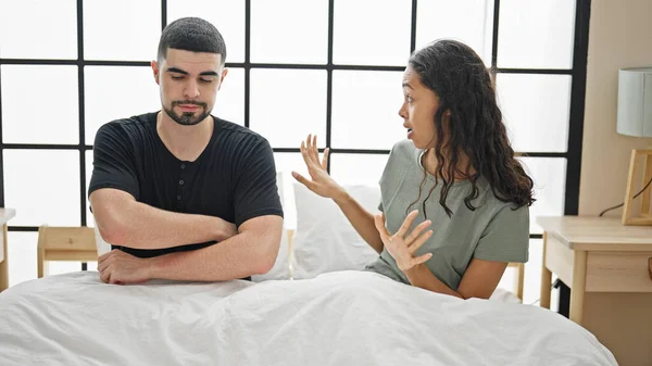 Beautiful couple arguing in bedroom, a serious disagreement amidst a lovely morning, stressed expression on their faces as they sit on bed in their home, a problem pulling them apart