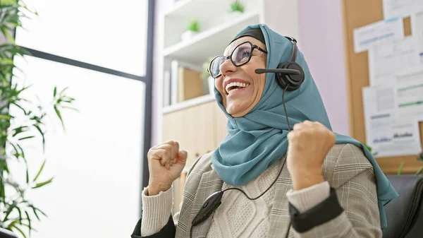 Jubilant Middle Aged Woman Hijab Headset Celebrates Office Environment Exemplifying — Stock Photo, Image