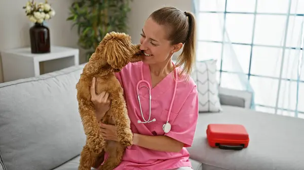 Young caucasian woman with dog veterinarian smiling confident holding dog kissing at veterinary clinic