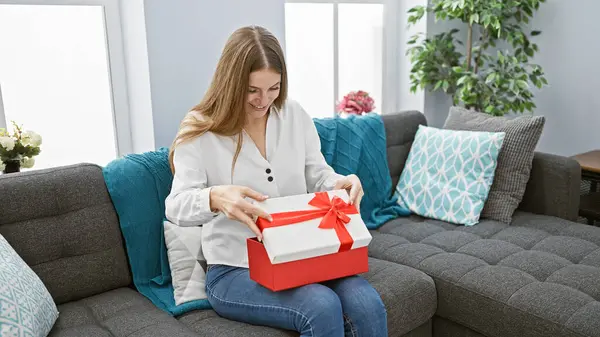 Uma Jovem Mulher Sorri Enquanto Abre Uma Caixa Presente Vermelha — Fotografia de Stock