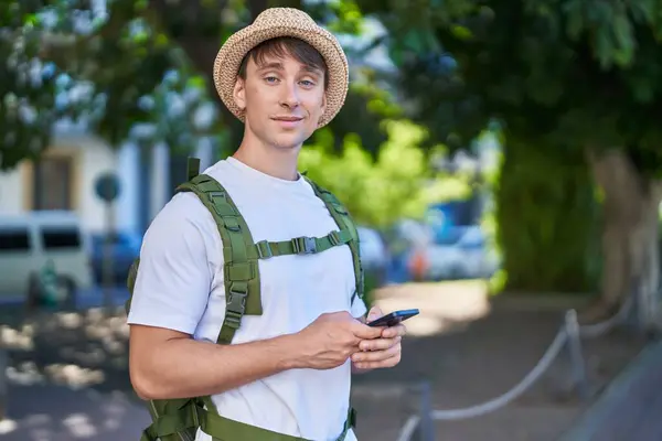 Young caucasian man tourist smiling confident using smartphone at park