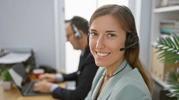 Two upbeat call center agents working together, smiling with confidence in the business office