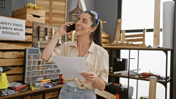 Confident Young Beautiful Hispanic Woman Carpenter Engrossed Reading Document While — Stock Photo, Image