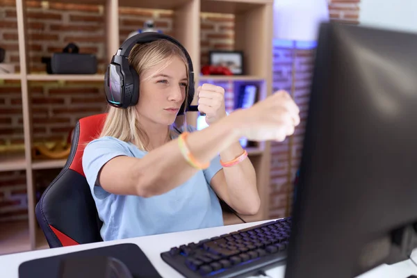 若い慎重な女性は戦うために拳を打つヘッドフォンを身に着けているビデオゲームをプレイし 攻撃的かつ怒った攻撃 脅威と暴力 — ストック写真