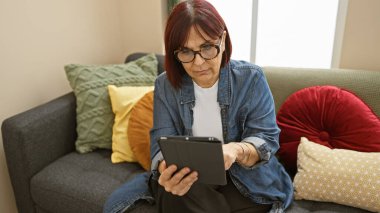 İçerideki koltukta tablet kullanan olgun İspanyol kadın..