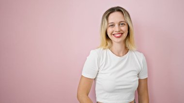 Young blonde woman smiling confident standing over isolated pink background
