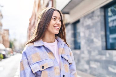 Young beautiful hispanic woman smiling confident looking to the side at street