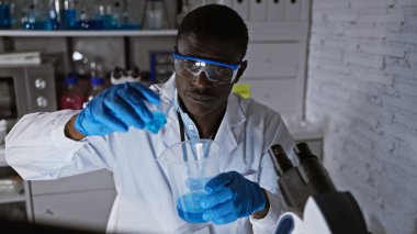 Laboratuvardaki Afrikalı adam deney tüpü ve mikroskopla araştırma yapıyor.