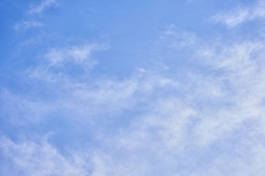 Pofuduk beyaz bulutların yüzdüğü sakin bir gökyüzü sahnesi parlak mavi bir zemin üzerinde, sükuneti ve açık alanı simgeliyor..