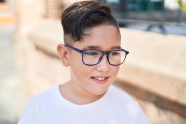 Adorable hispanic boy smiling confident looking to the side at street