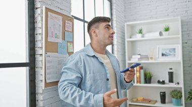 Genç, yakışıklı İspanyol iş adamı ofis içinde çalışırken akıllı telefonundan hayati bir sesli mesaj yolluyor.