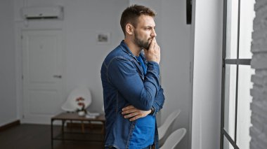 Yakışıklı, genç İspanyol bir adam, düşüncelere dalmış, bekleme odasının penceresinden bakıyor, havalı ama ciddi bir ifadeyi canlandırıyor. Sıradan yaşam tarzını sergileyen kapalı mekan portresi.