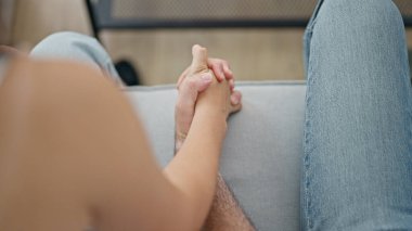 Güzel bir çift kanepede oturuyor ve elleri birbirine kenetlenmiş.