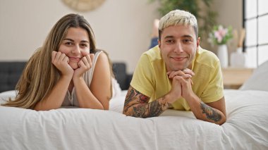 Yatak odasında yatarken kendine güvenen güzel bir çift.