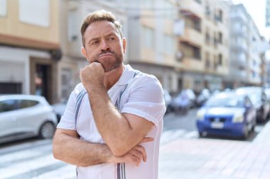 Middle age man standing with doubt expression at street