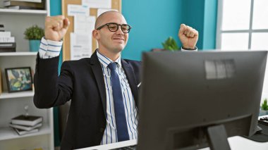 Genç İspanyol iş adamı ofiste kutlama için bilgisayar kullanıyor.