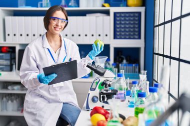 Genç ve güzel İspanyol bilim kadını. Laboratuvarda elma okuma belgesi tutuyor.