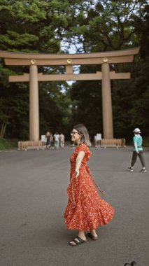 Neşeli İspanyol kadın kollarını açmış gülümsüyor, Meiji tapınağına bakıyor, kendine güvenini ve mutluluğunu gösteriyor.