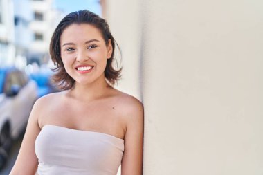 Genç İspanyol kadın gülümsüyor. Kendine güveni tam. Caddeye bakıyor.