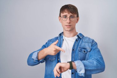 Beyaz, sarışın, gözlüklü adam acele edip saati, sabırsızlığı ve gecikmeye kızmayı işaret ediyor. 