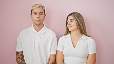 Soyutlanmış pembe arka planda ciddi yüzleri olan güzel bir çift.