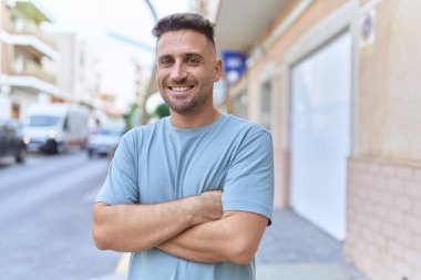 Sokakta kollarını kavuşturmuş İspanyol genç bir adam.