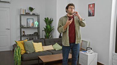 Modern bir oturma odasında akıllı telefon kullanan İspanyol bir adam, çağdaş dekorlu rahat bir ev ortamını canlandırıyor..