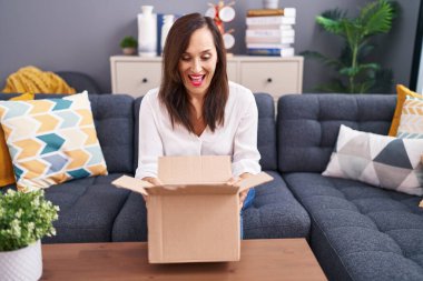 Orta yaşlı esmer kadın karton kutuyu açıp çılgınlığı kutluyor ve başarıya hayret ediyor gözleri açık heyecanla haykırıyor.. 